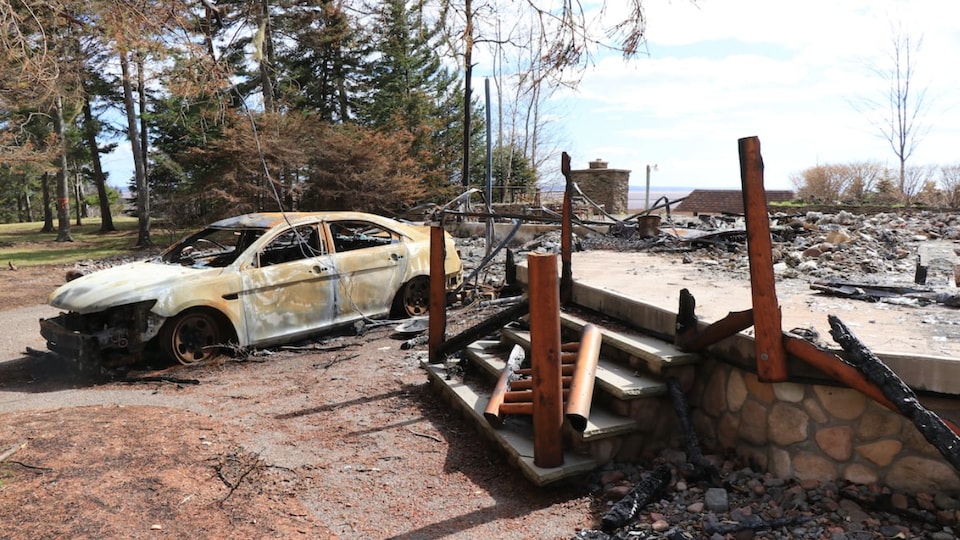 The burning ruins of a chalet and the corpse of a burnt car.