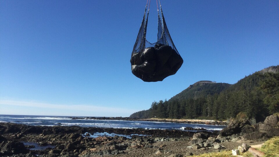 Un sac de débris transporté au dessus d'une plage.