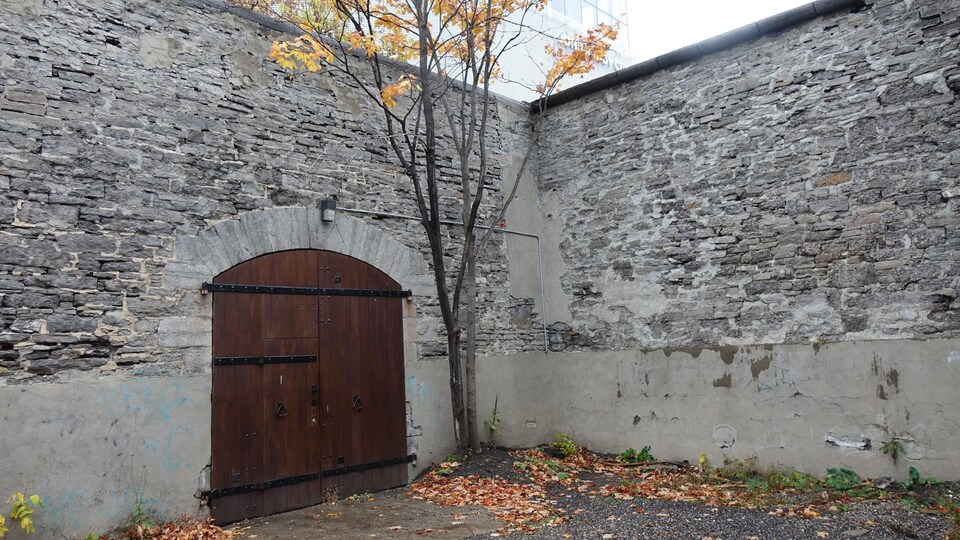 Une porte de bois massif se découpe dans un mur de pierre effrité.