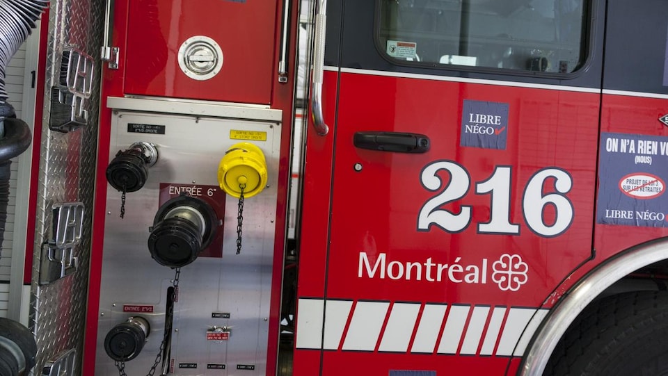 Détail de la portière d'un camion de pompiers de Montréal arborant des autocollants de revendications syndicales.