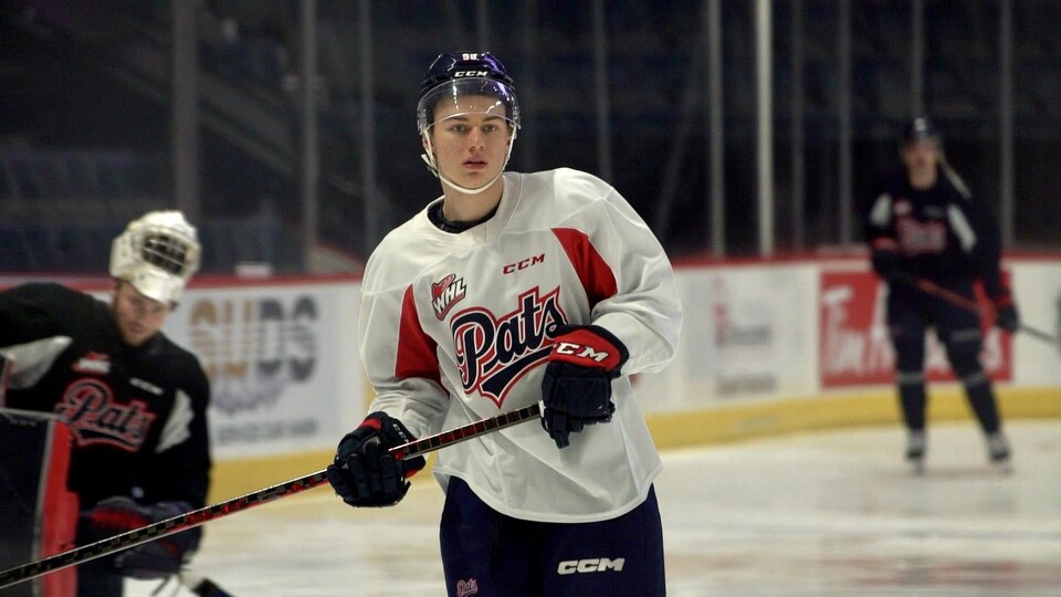 Connor Bedard porte son équipement à l'occasion d'un entraînement au Brandt Centre.