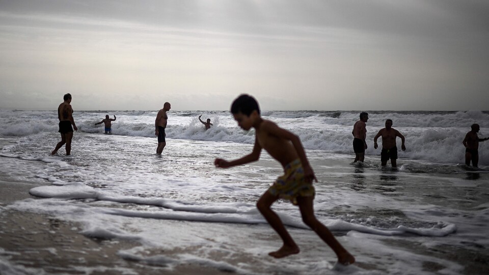 Plusieurs personnes nageant dans l'océan atlantique à Oeiras, au Portugal, pour célébrer le Nouvel An.