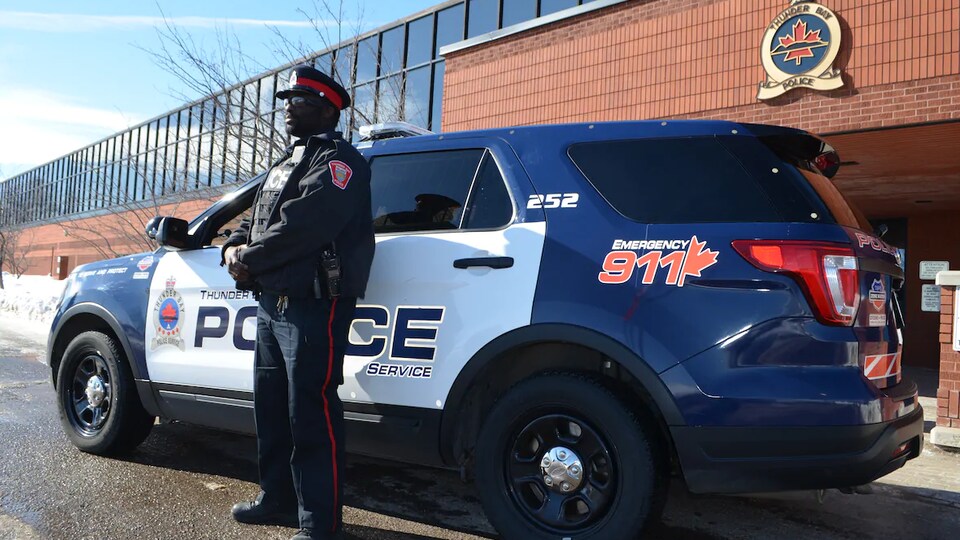 Un policier à côté d'un véhicule de patrouille devant le quartier général de la police de Thunder Bay.