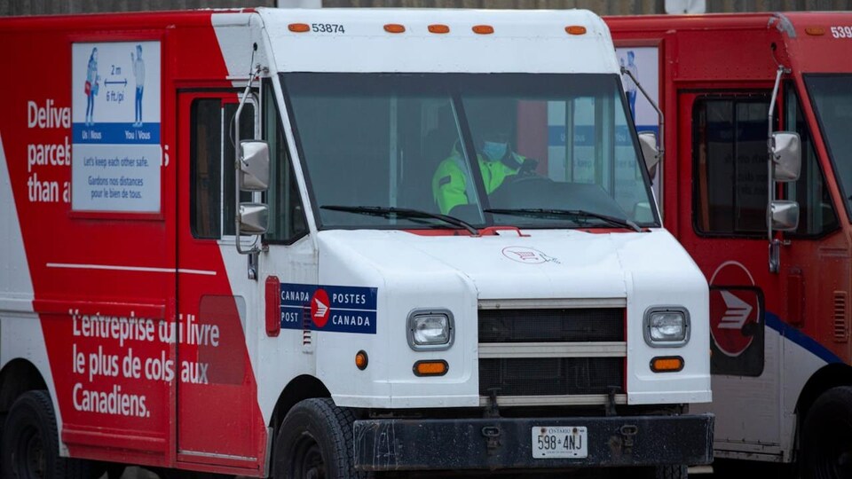 Un employé à bord d'un camion de livraison de Postes Canada stationné devant le centre de tri Gateway-Est.