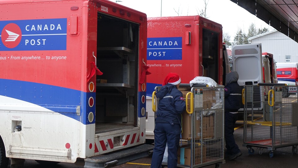 Une factrice remplit un camion de livraison de Postes Canada.