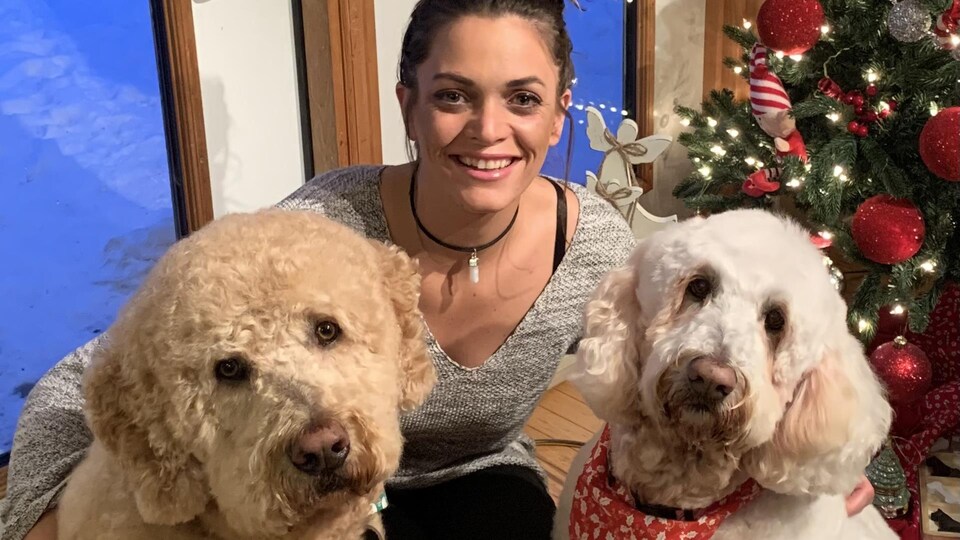 Dayna Karle enlace deux chiens devant un arbre de Noël.