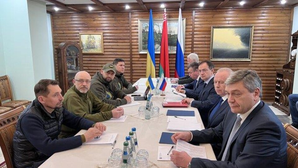 Des hommes sont assis de part et d'autre d'une table.