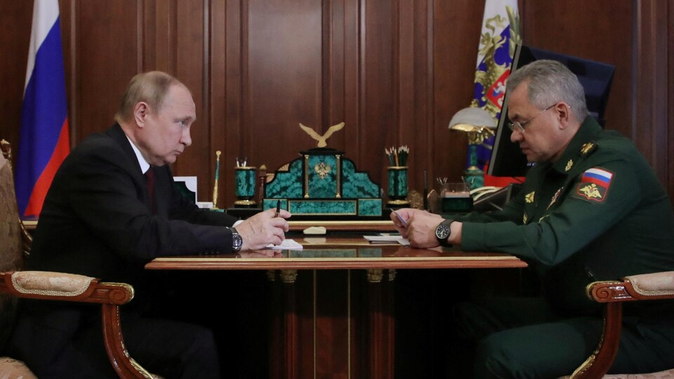 Vladimir Poutine fixe Sergueï Choïgou, qui lit un texte.