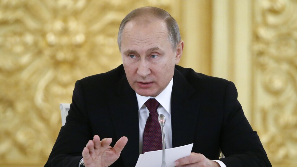Vladimir Poutine tient des documents dans ses mains.