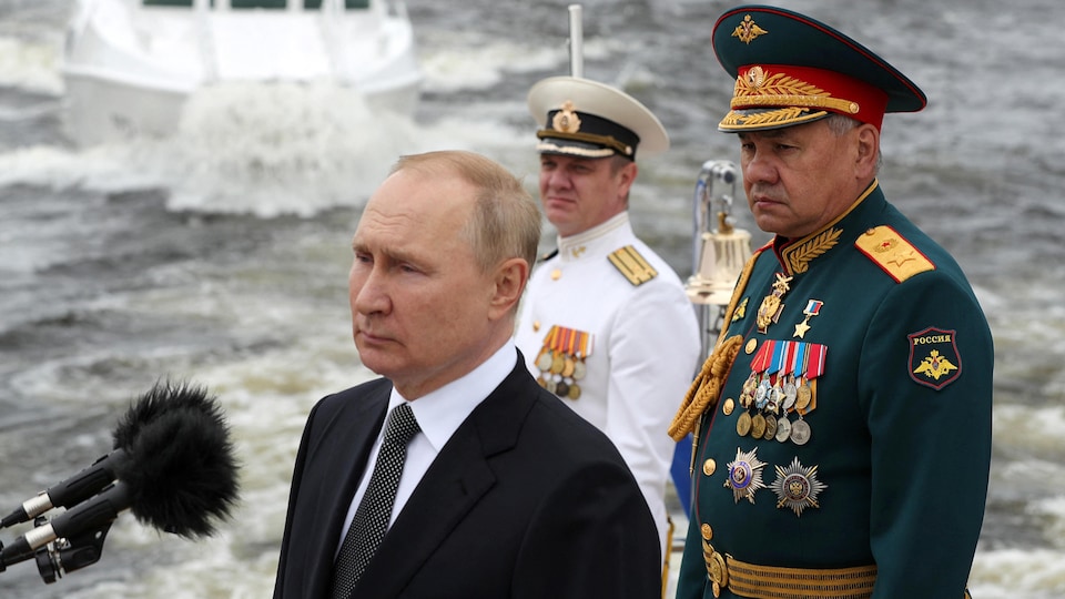 Rusya Devlet Başkanı Vladimir Putin (solda), Savunma Bakanı Sergei Shoigu'nun yanında duruyor.