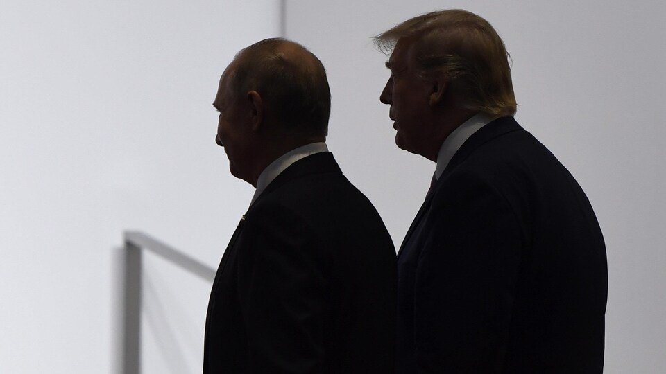 Les présidents Trump et Poutine, qu'on voit de profil, marchant côte à côte.