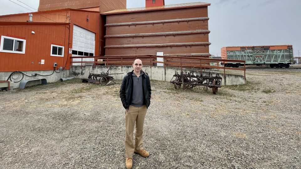 Emanuel Neves debout devant un silo à grains.