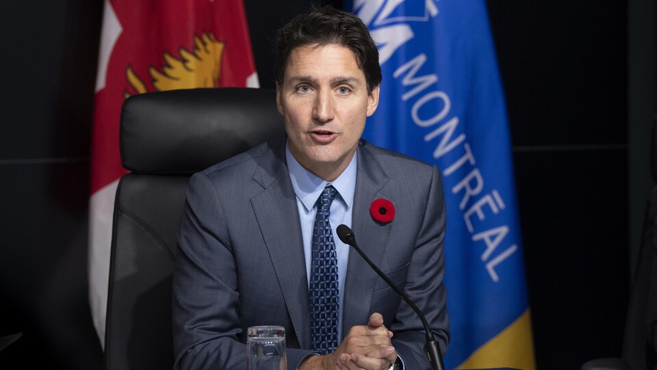 Justin Trudeau parle dans un micro les mains jointes. 