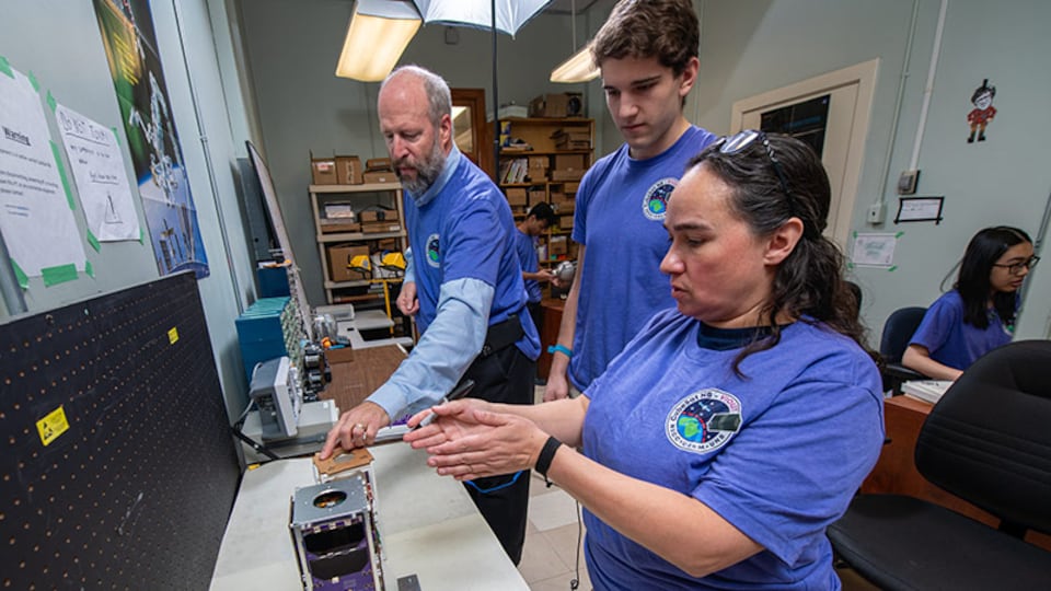 UNB teacher Brent Petersen (left) and students work on Violet, New Brunswick's first satellite to travel into space.