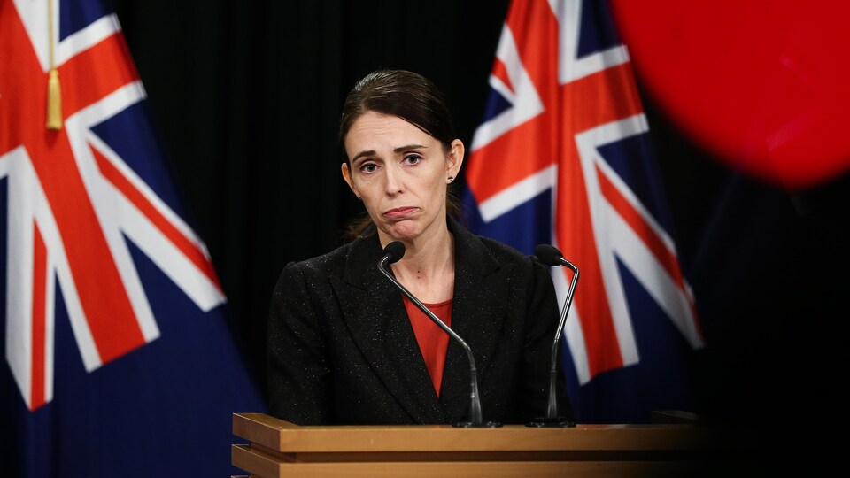 La première ministre Jacinda Ardern s'adresse à la presse le visage sombre. 