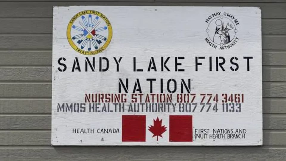 Une affiche dans la Première Nation de Sandy Lake donnant des numéros d'urgence.