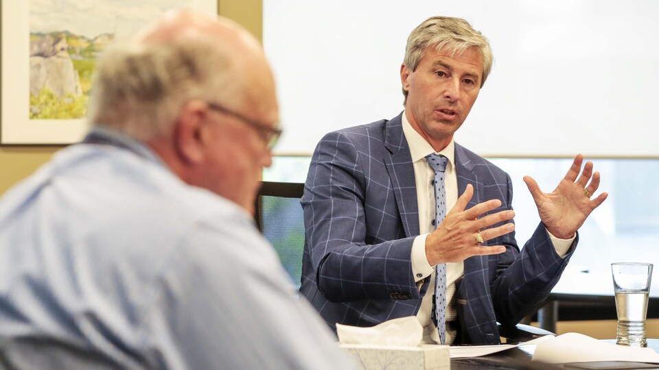 Tim Houston et Robert Strang sont assis à une table de réunion et discutent.