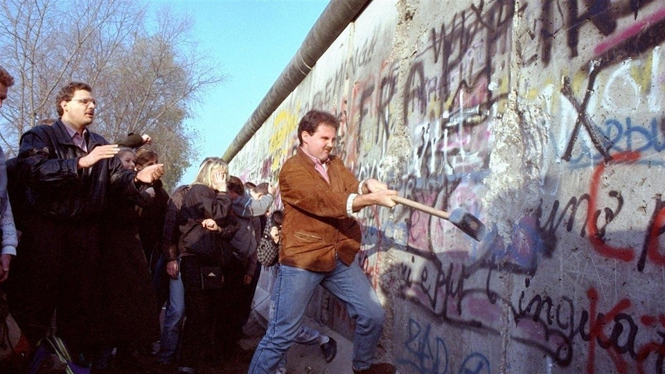 Un homme tente de faire tomber une partie du mur de Berlin, le 12 novembre 1989.