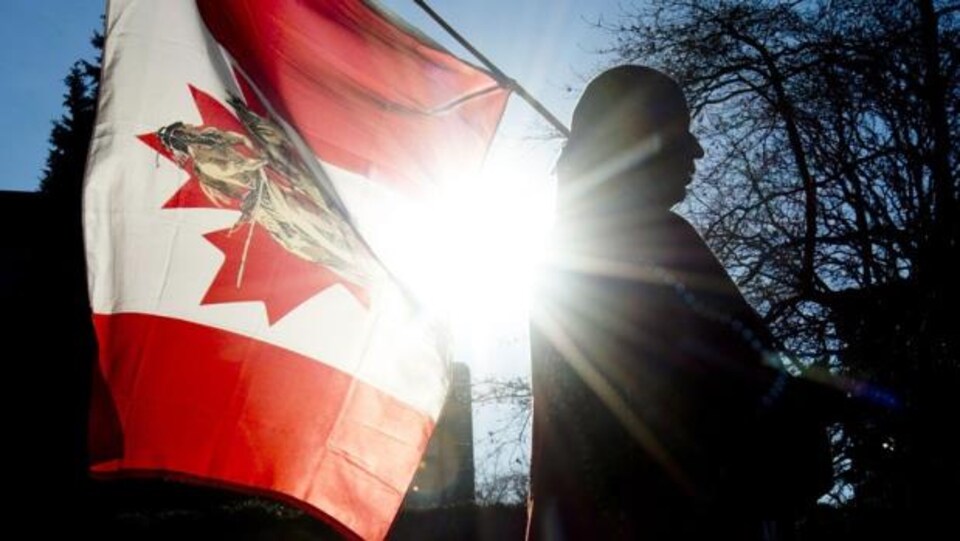 Photo d'un membre d'une Première Nation avec un drapeau canadien.