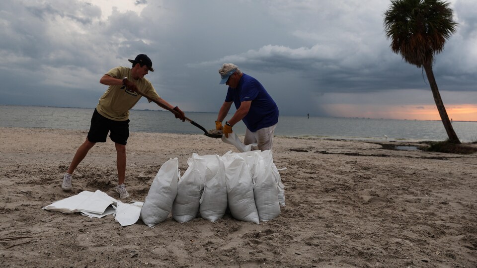 Deux personnes remplissent des sacs de sable.