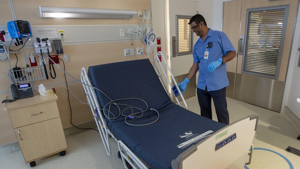 Un préposé aux bénéficiaires désinfecte un lit d'hôpital.