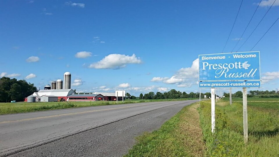 Une affiche le long d'une route devant une ferme