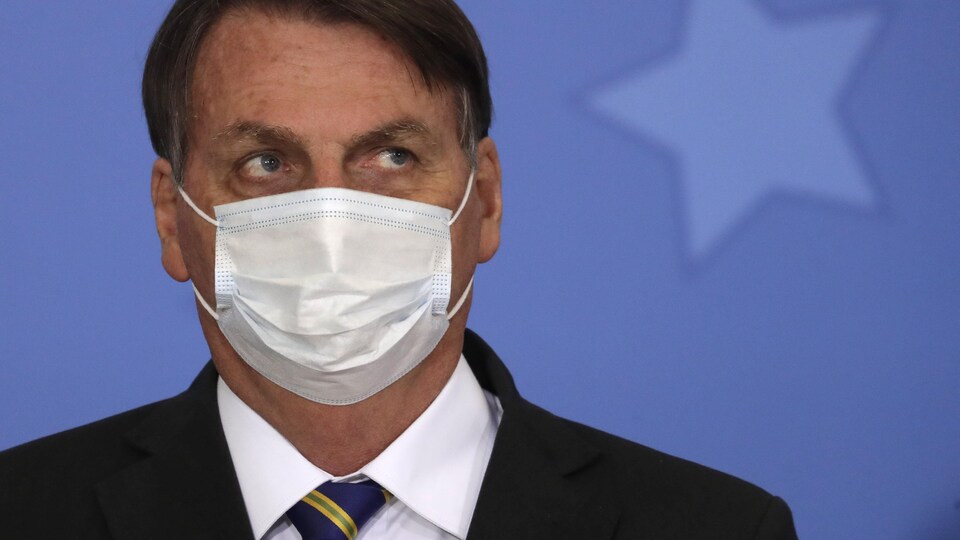 Jair Bolsonaro regarde vers le haut en portant un masque.