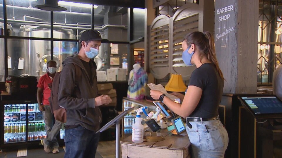 L'hôtesse d'accueil du restaurant regarde le papier de vaccination du client.