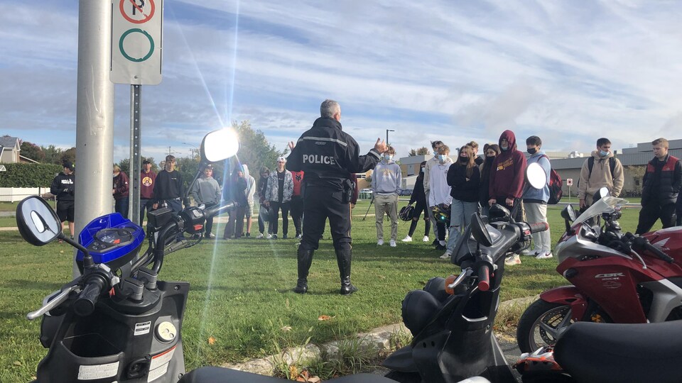 Un policier parle devant des jeunes.