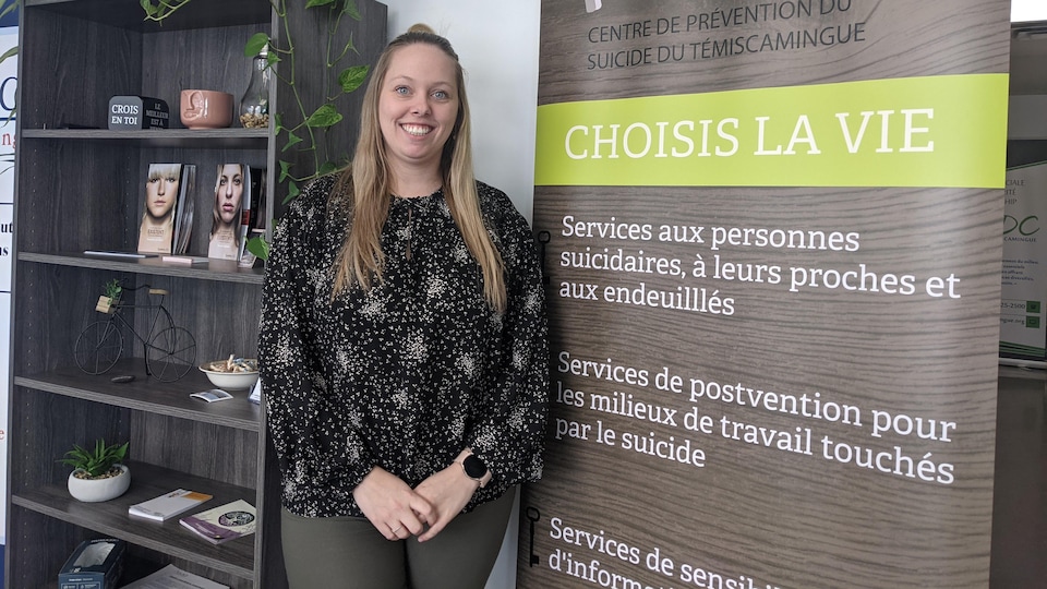 Anabelle Landry-Genesse, directrice générale du Centre de prévention du suicide du Témiscamingue, se tient devant une affiche de prévention du suicide. 