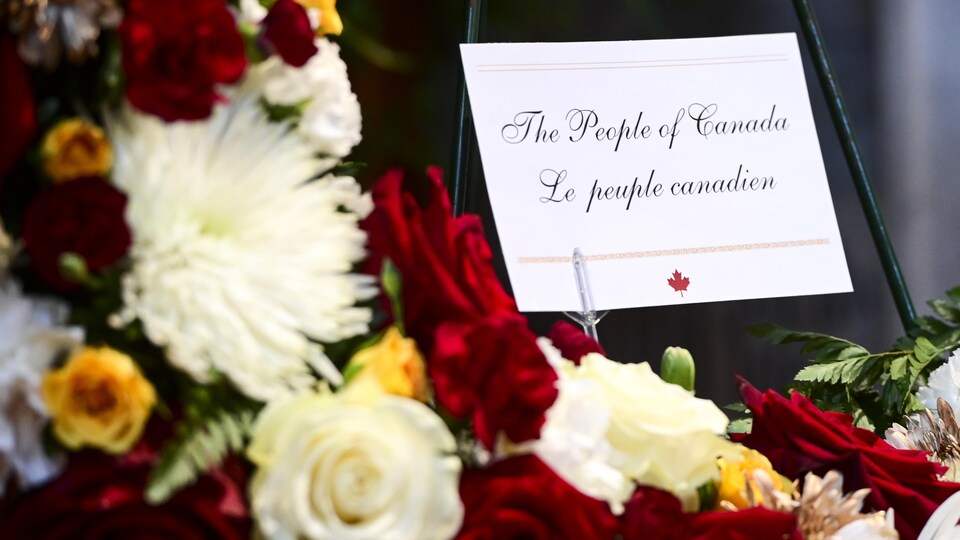Une couronne de fleurs avec au milieu un carton où est écrit « The People of Canada - Le peuple canadien ».