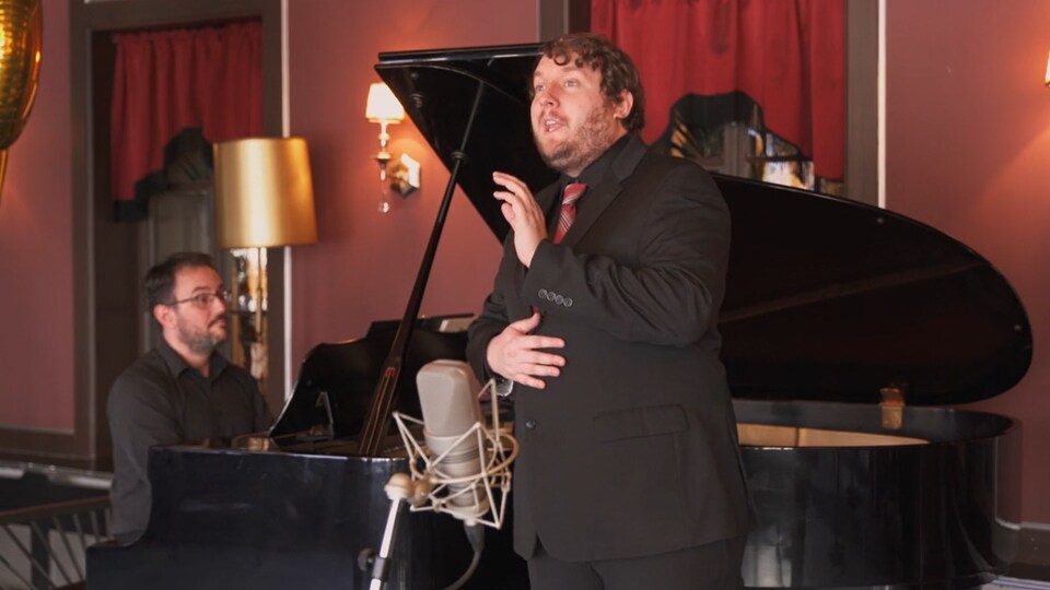 Un chanteur d'opéra devant un piano à queue. 
