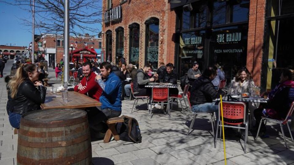 Plusieurs groupes de personnes sont attablés sur la terrasse d'un restaurant du marché By.