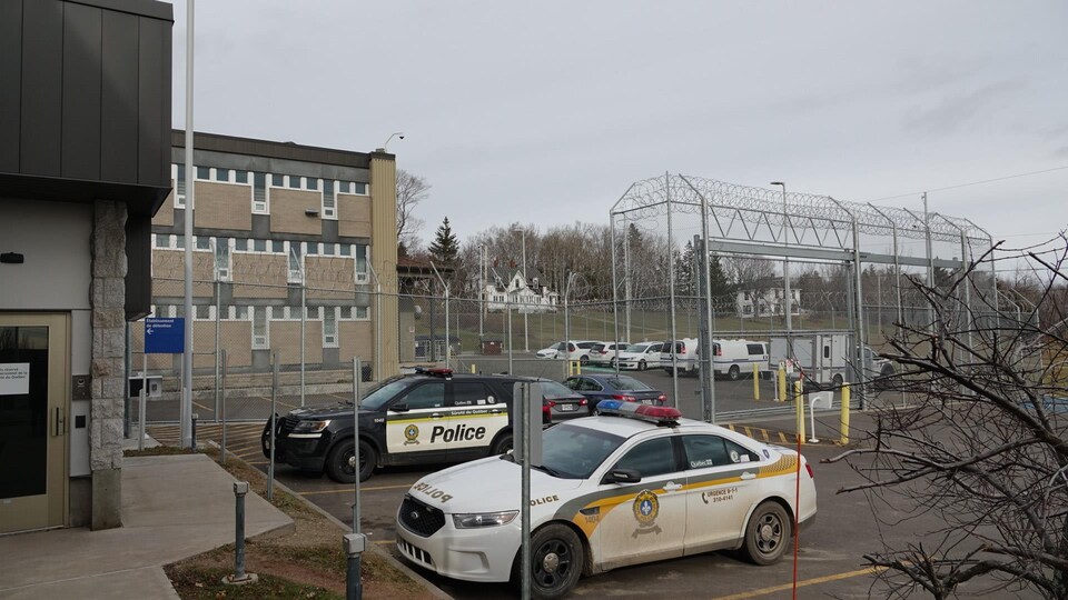 Des véhicules de la Sûreté du Québec sont garés devant le centre de détention de New Carlisle, entouré de clôtures munies de fils de fer barbelés.