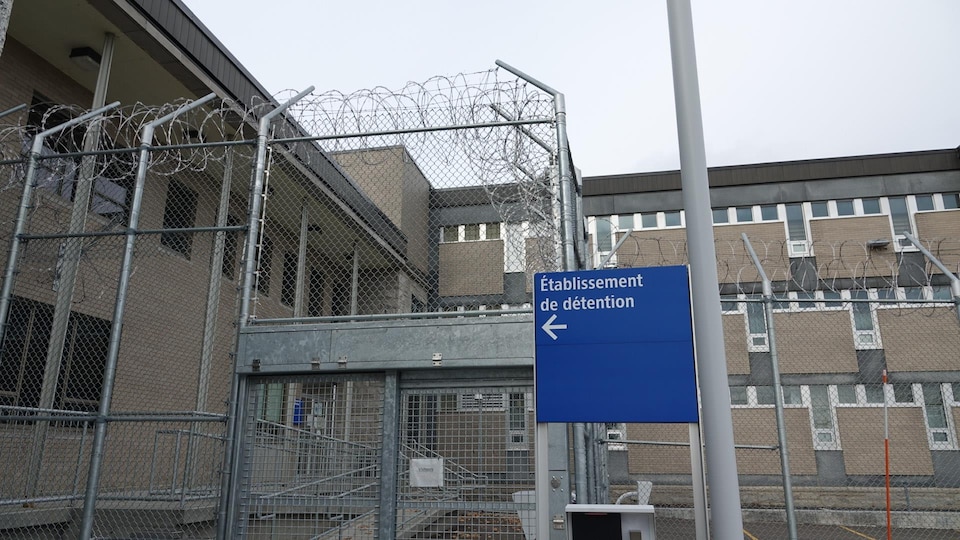 Un panneau indique l'entrée du centre de détention de New Carlisle, entouré de clôtures munies de fils barbelés.