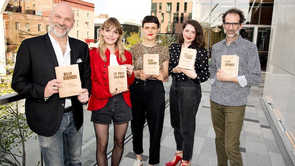 Deux hommes et trois femmes posent avec des trophées en bois en forme de livre. 