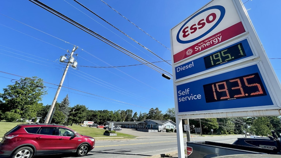 Une voiture passe près d'une pancarte qui indique les prix de l'essence.