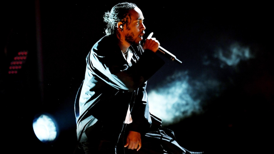 Kendrick Lamar, habillé de noir, en train de chanter sur scène lors d'un gala des prix Grammy.
