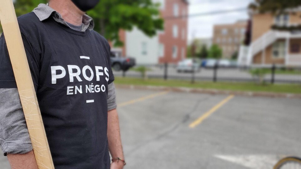 Un enseignant tient une pancarte dans une manifestation.