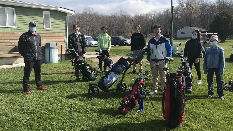 Un enseignant et six élèves avec leurs sacs de golf.
