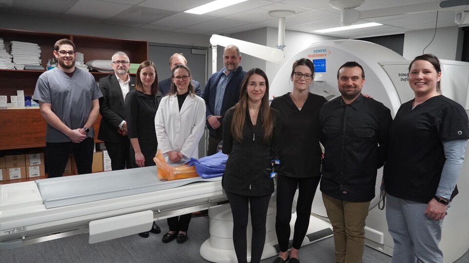 Plusieurs étudiants et membres de la direction du Cégep de Rimouski posent devant un appareil d'imagerie médicale. 