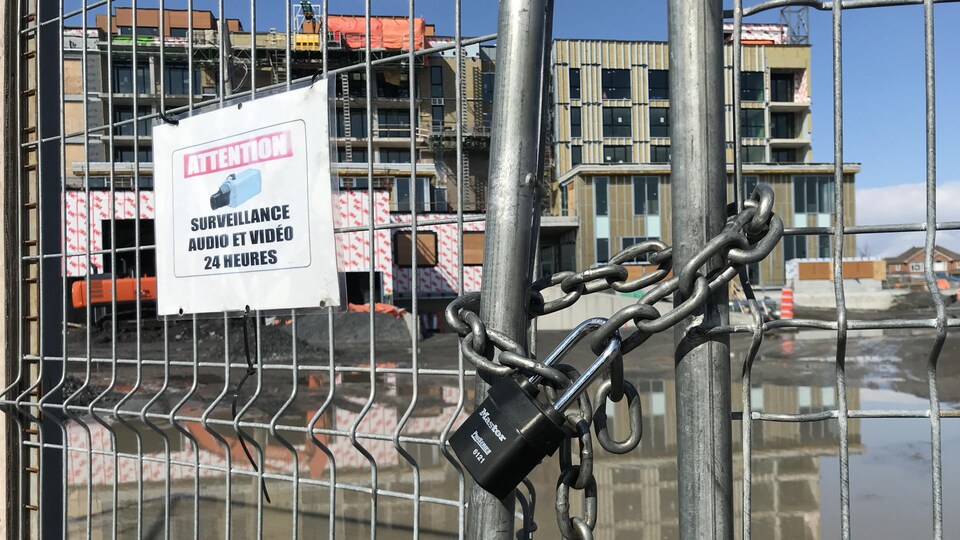 Un cadenas ferme des barrières devant un chantier de construction