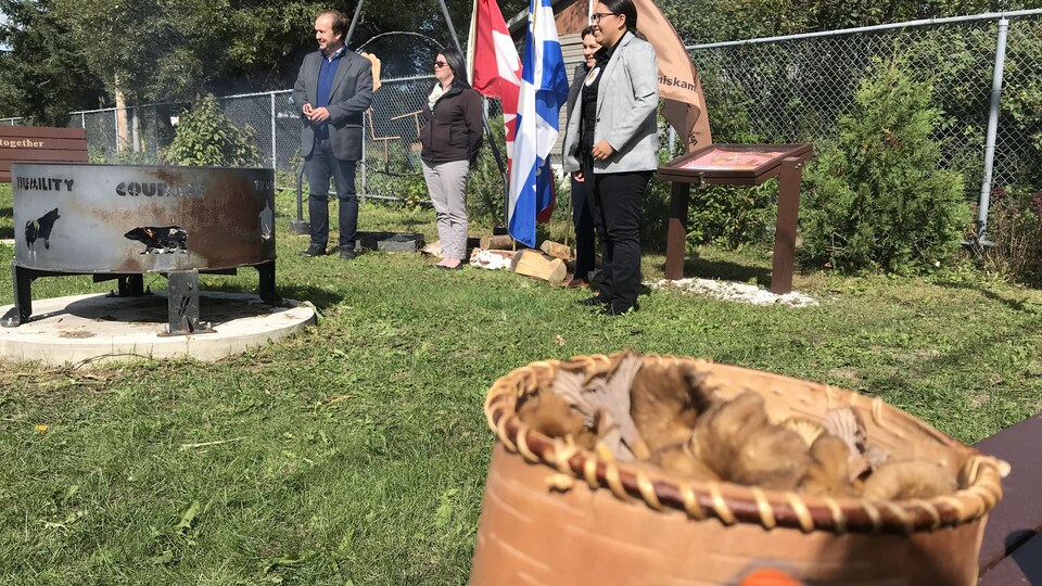 Des membres de la communauté de Timiskaning sont dehors avec le ministre des Ressources naturelles, Paul Lefebrevre, à côté d'un sac de champignons forestiers.
