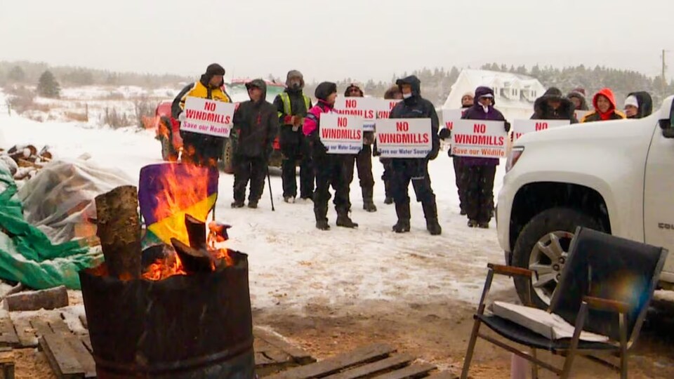 Des manifestants tiennent des affiches d'opposition à un projet de parc éolien.