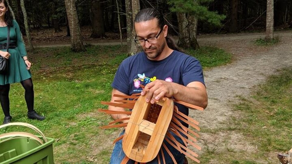 Un homme qui réalise un panier de frêne dans la nature.