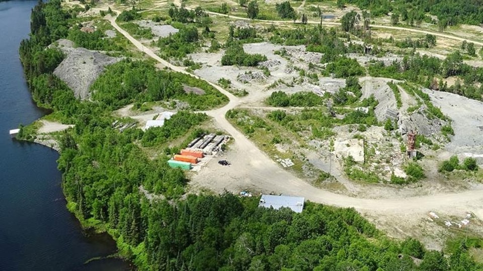 Vue aérienne d’une installation d’exploration minière en forêt près d’un lac. 