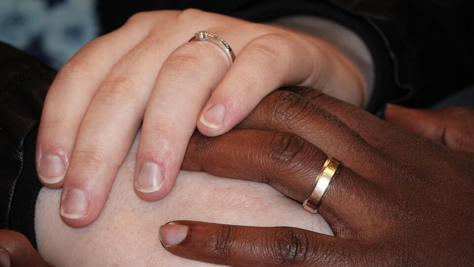 Les mains d'un homme et d'une femme portant chacun une alliance.