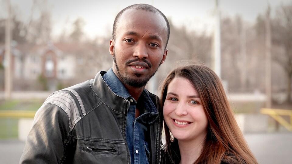 Un homme et une femme souriant à la caméra.