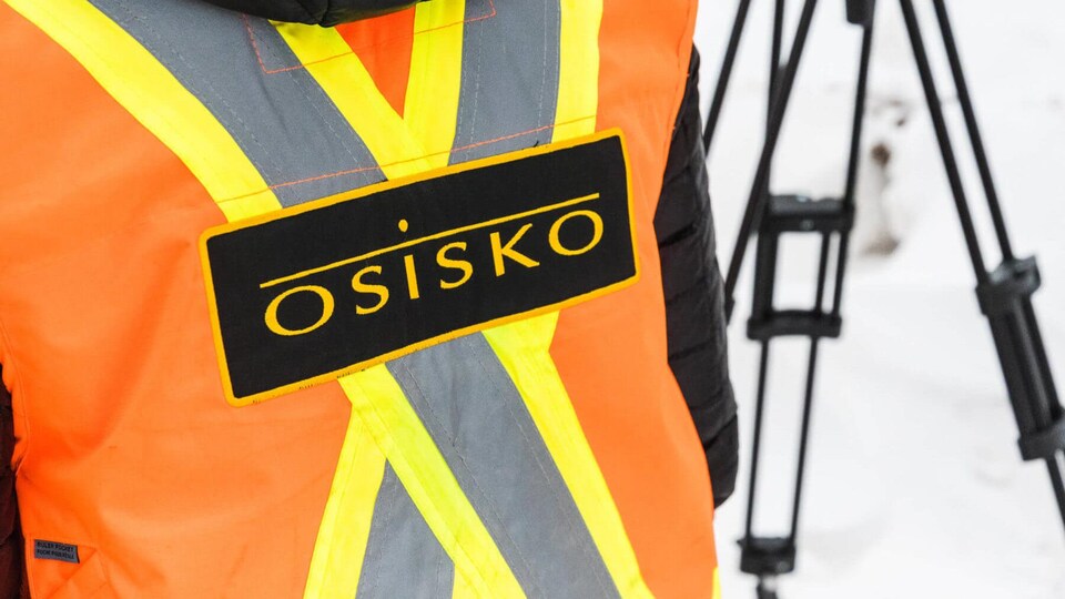 Une personne vêtue d'une veste de sécurité, avec le logo d'Osisko dessus.