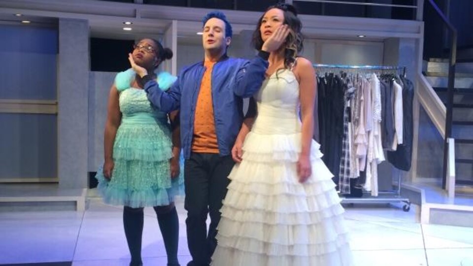 Trois comédiens, dont deux filles en robes de dentelle, répètent une scène.